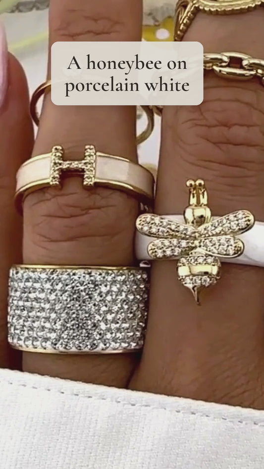 Shahd honeybee ring with a pavé gold bee on a glossy white band, shown up close on the hand