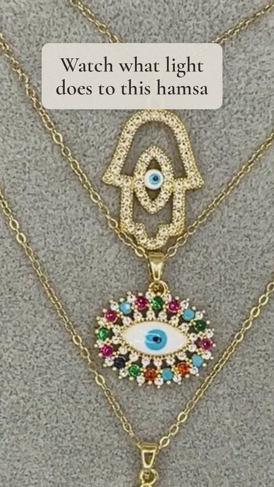 Noor Hamsa evil eye pendant in 18K gold plating catching the light up close